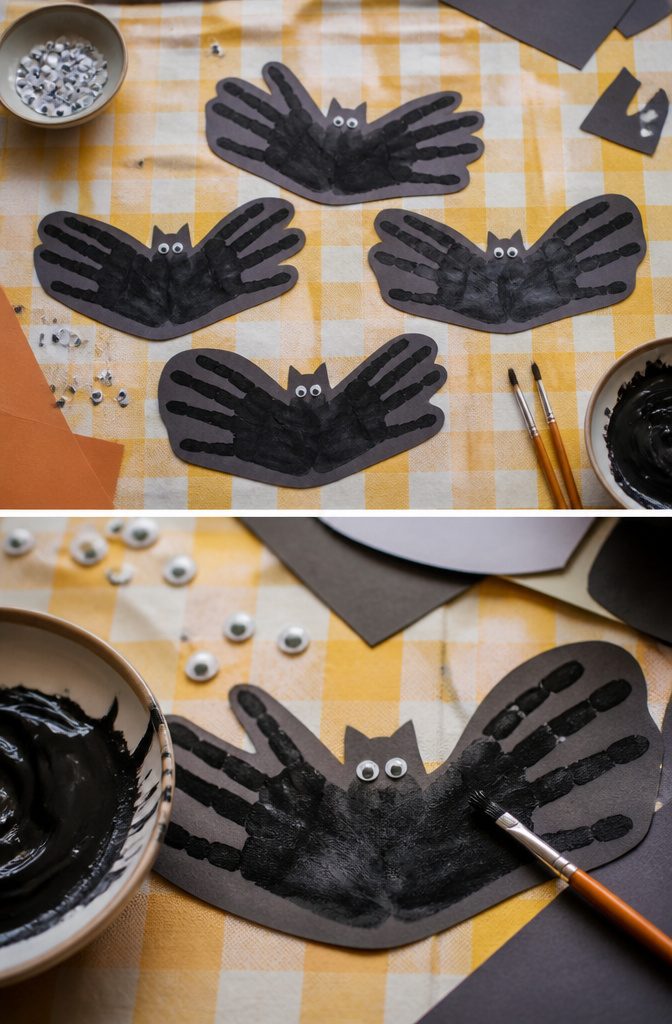 Child's handprint painted black forming a bat shape on paper.