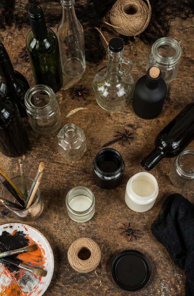 An assortment of bottles and crafting materials for Halloween decor.