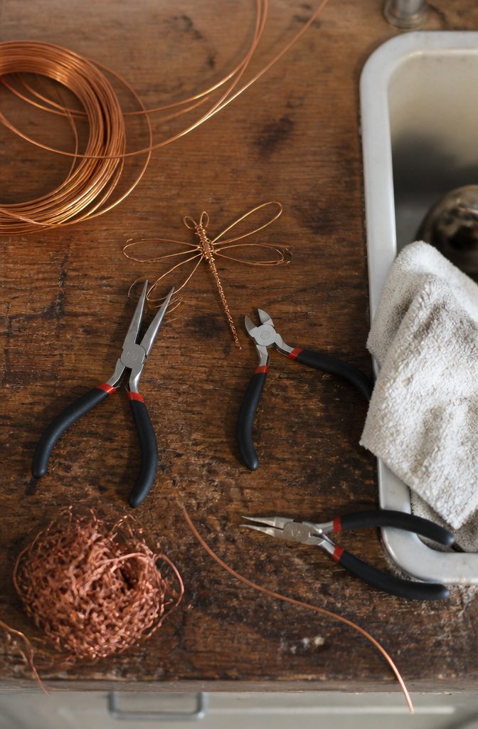 Wire cutters and pliers on a wooden surface.