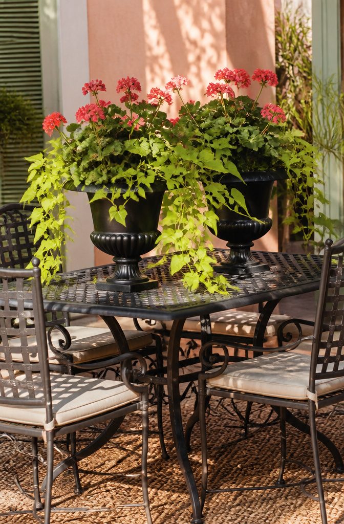 Black urn planters displayed on a porch with plants inside.