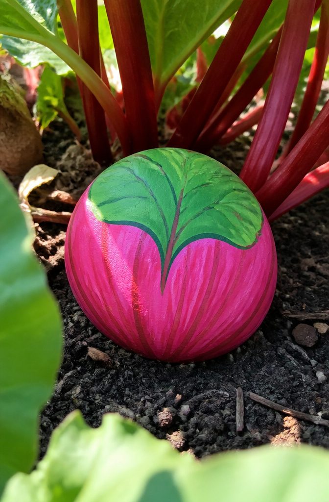 A stone painted bright pink and green to resemble rhubarb.